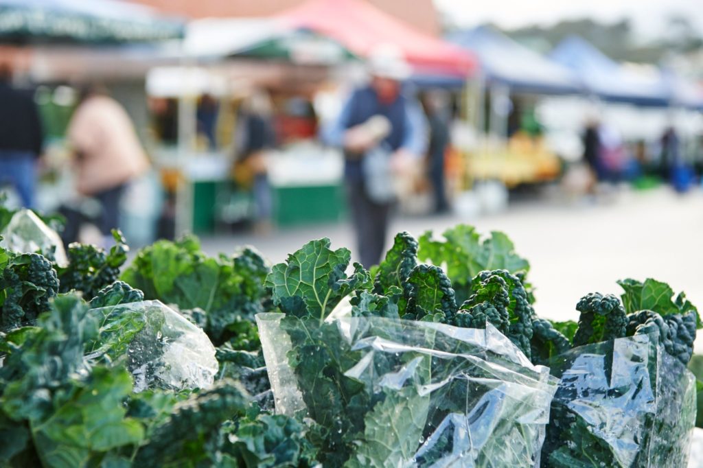 A macro shot of kale with market stalls in the background show the fresh produce to eat on The South West Edge south western australia road trip