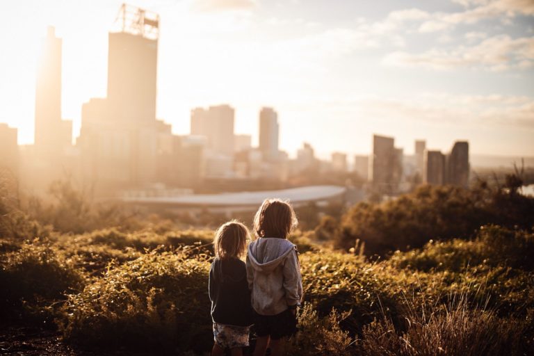 Two young boys face a view of Perth City at sunrise to show the beauty of the city juxtapositioned with nature at Kings Park