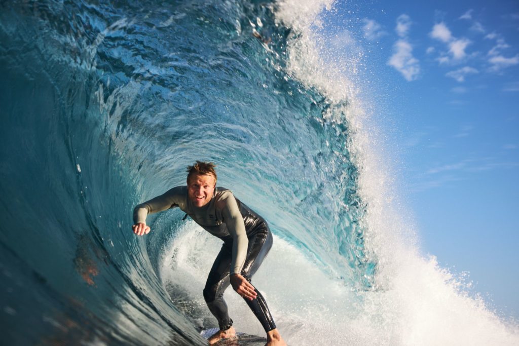 A man surfs a perfect wave in Margaret River to show this adventurous activity on this south west australia road trip