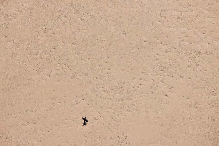 A drone shot of a surfer on a secluded beach to show the vast natural landscape along the south western australia road trip The Edge