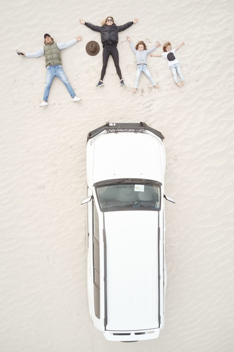 A drone image shows a family making snow angels in the white sand of Esperance Sand Dunes next to a four wheel drive vehicle to show the family fun had on this Perth to Esperance road trip