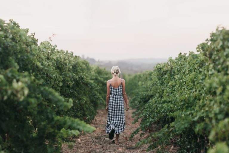 A girl in a dress walks through a green vineyard to show the gourmet delights and attractions to see while on the perth to esperance road trip The Edge