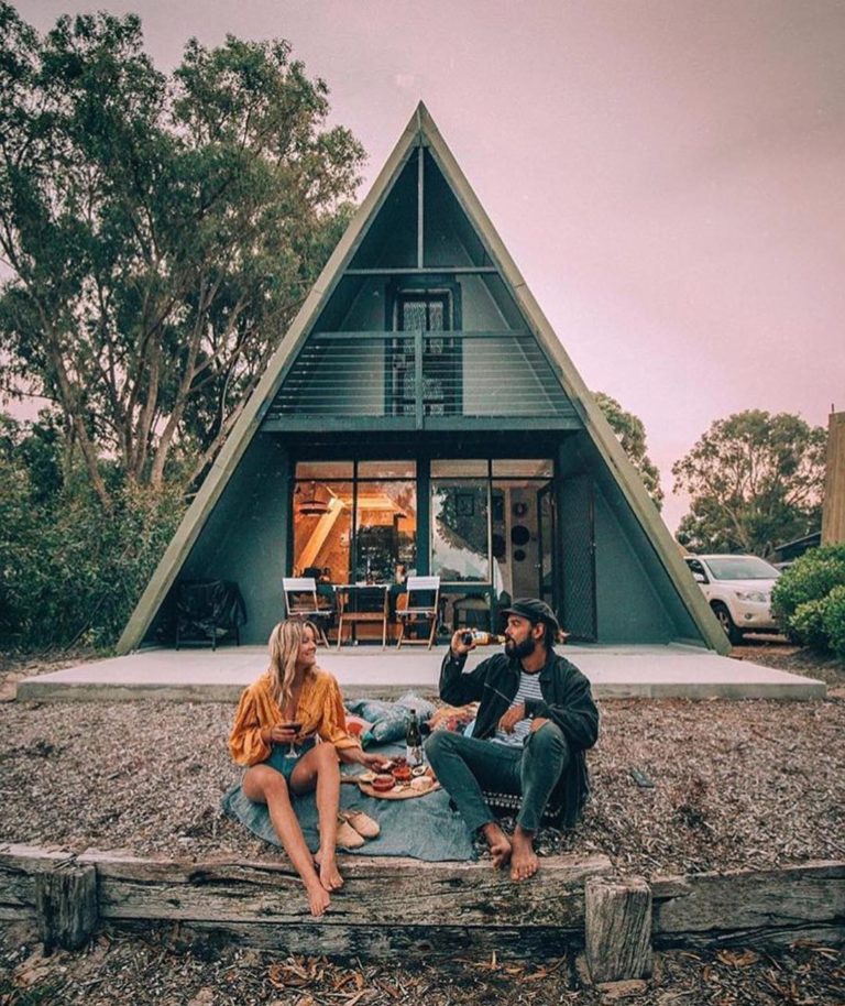 Esperance Chalet Village couple sit outside teepee chalet at sunset shows quirky accommodation options on Perth to Esperance road trip