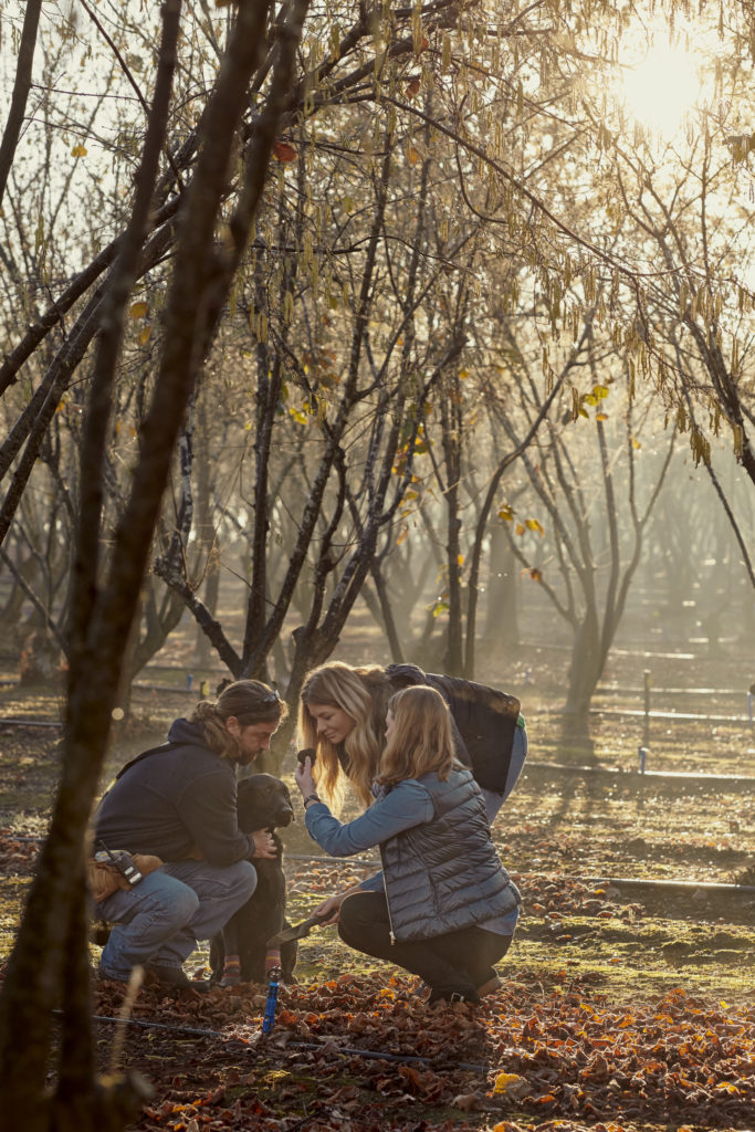 A portrait image of man on truffle hunt with two women smelling fresh truffle to show luxury experiences en route along The Edge
