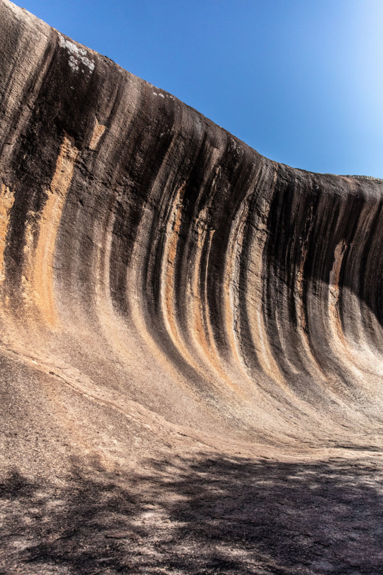 portrait image of rock face shaped like a wave with blue sky to show incredible landscapes on the south west edge road trip
