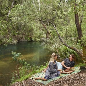A landscape image of a couple enjoying a picnic by a green pool to show camping spots along The South West Edge road trip