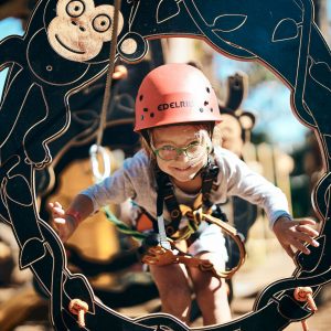 A small child wears a helmet and climbs through a monkey rope course to show family fun adventure activities to do while on this road trip down south western australia