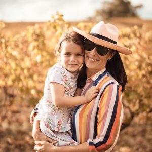 A mother and daughter hug and smile in a vineyard to show happy times along The South West Edge road trip