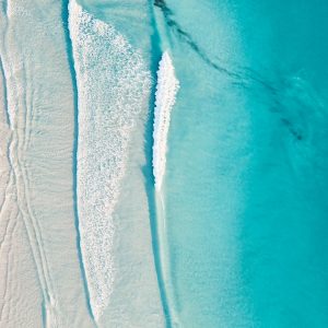 An aerial shot of pristine turquoise blue waves lapping on a white sandy beach to show untouched coastline found on the perth to esperance australia road trip