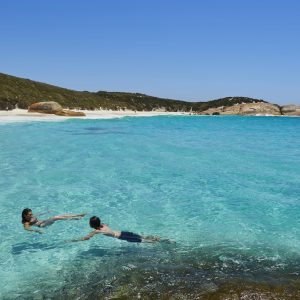 a couple swim in pristine crystal clear waters near Albany to show beaches in summer en route along The South West Edge road trip