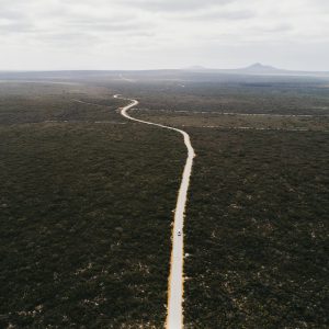 A drone shot of a long road and wide landscape with mountains in the distance