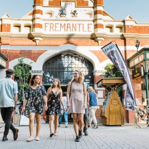 A group of young people walk outside the iconic brick Fremantle Markets building to show shopping and cultural experiences to be had on The South West Edge road trip