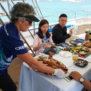 An image of a family being served fresh seafood while on a boat to show gourmet culinary experiences and tours while on The South West Edge road trip