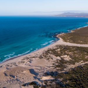 drone image of blue ocean next to landscape to show natural vistas en route along the edge