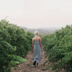 A girl in a dress walks through a green vineyard to show the gourmet delights and attractions to see while on the perth to esperance road trip The Edge
